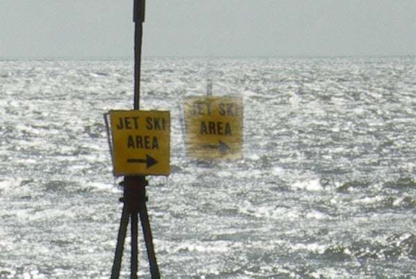 Jet ski area signs on a choppy water body.