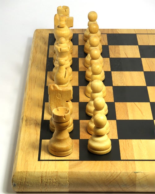 Wooden chess pieces set up on a chessboard