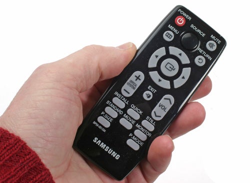 Hand holding Samsung SP-P400B portable projector remote control.