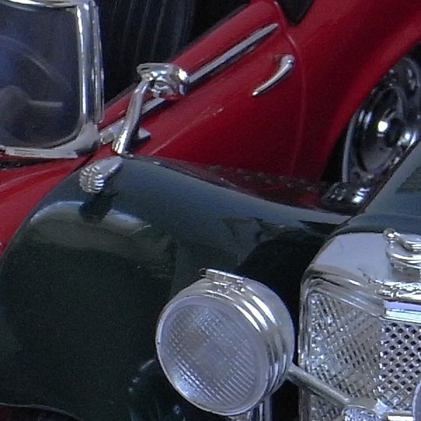 Close-up of a vintage red and black car with chrome details.