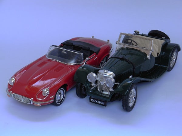 Two classic model cars on a blue surface.