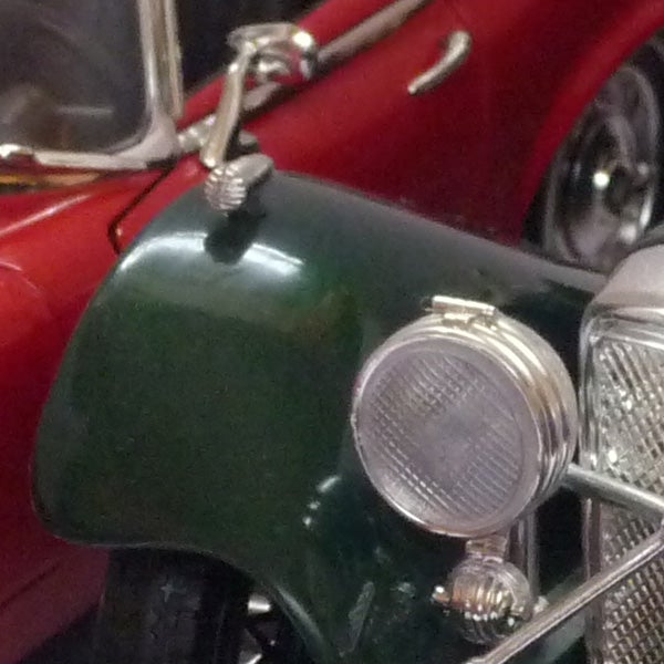 Close-up of a vintage car headlight and front grille.