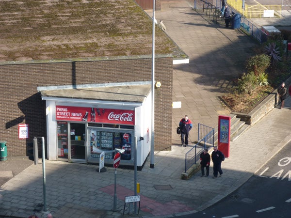 Aerial view of a small street newsstand with pedestrians.