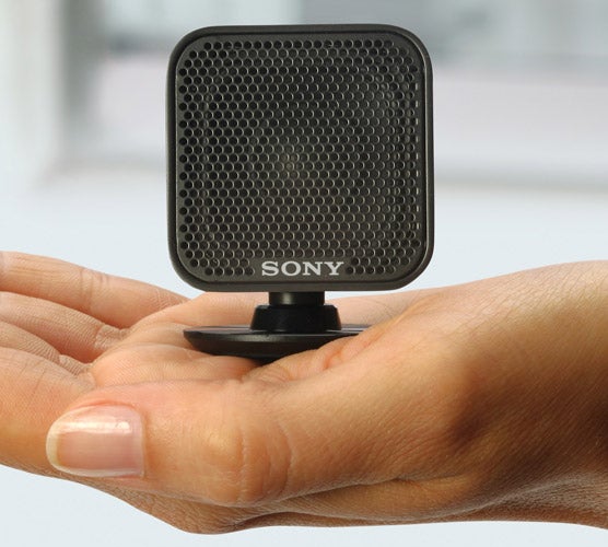 Hand holding a Sony speaker from home cinema system.