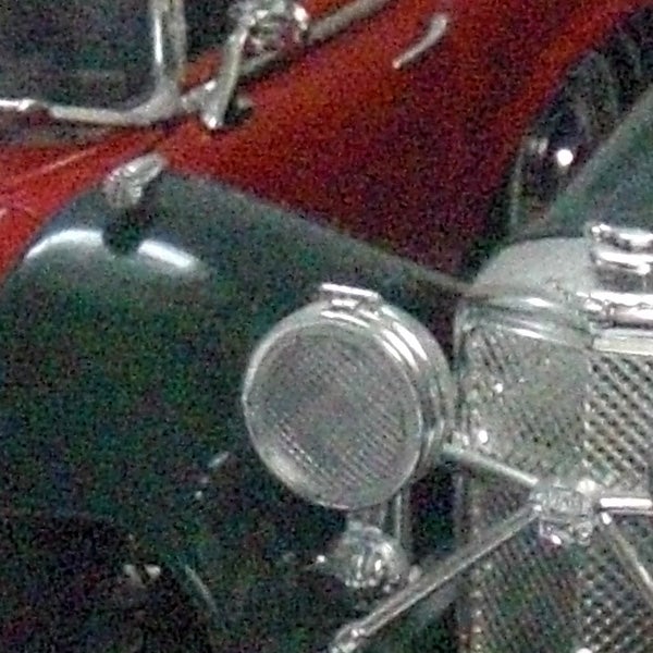 Close-up of a vintage car's headlight and grille.