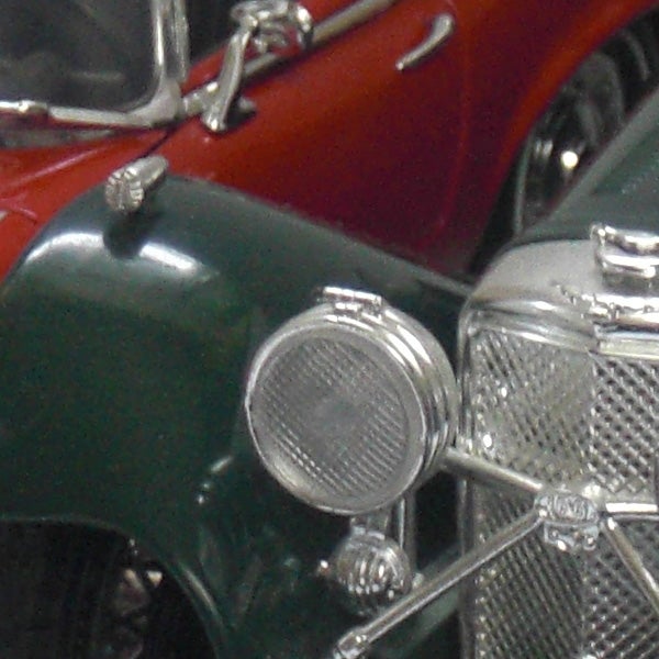 Close-up of a vintage car model headlights and grille.
