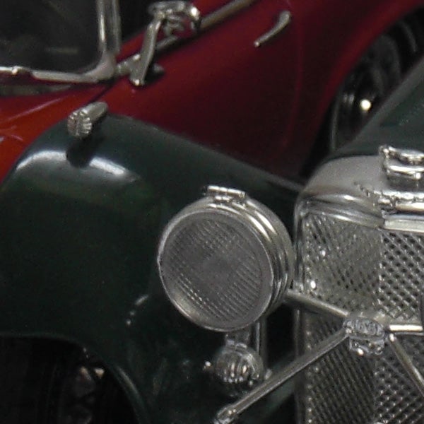 Close-up of vintage car details, showing headlight and grille.