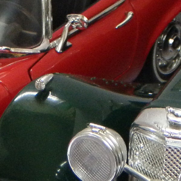 Close-up of vintage model cars, one red and one green.