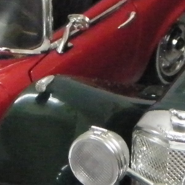 Close-up of a red toy car and clear green car.