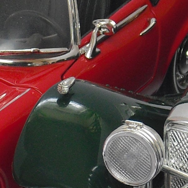 Close-up of a vintage red car details with chrome headlamps.