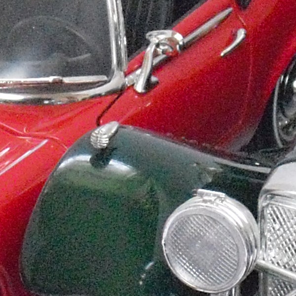 Close-up of a vintage red and green car's front side.