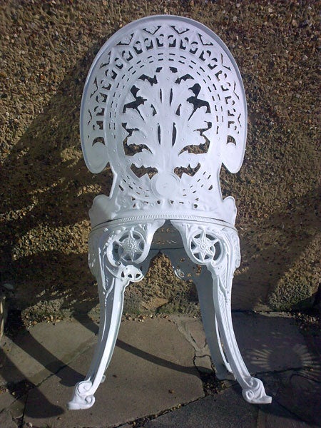 White ornate metal chair against a textured wall.