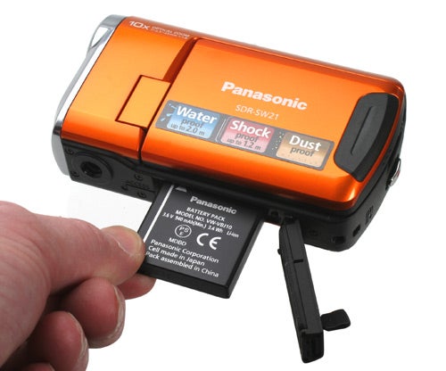Hand inserting battery into Panasonic SDR-SW21 camcorder.