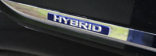Close-up of Lexus LS600h L hybrid badge on car.