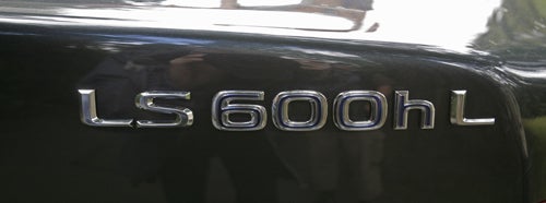 Close-up of Lexus LS600h L model designation on car.