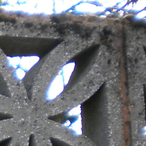 Close-up of intricate metal pattern with light shining through.