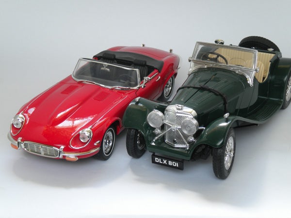 Two model cars, a red Jaguar E-Type and a green Aston Martin.