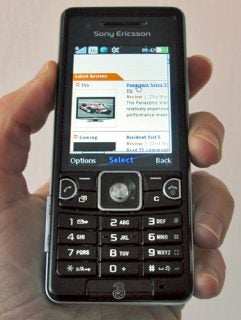 Hand holding a Sony Ericsson C510 Cyber-shot phone displaying screen.