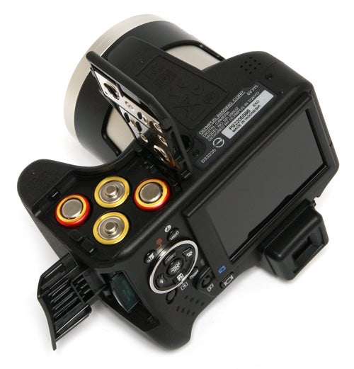 Olympus SP-590UZ camera showing battery compartment and screen.