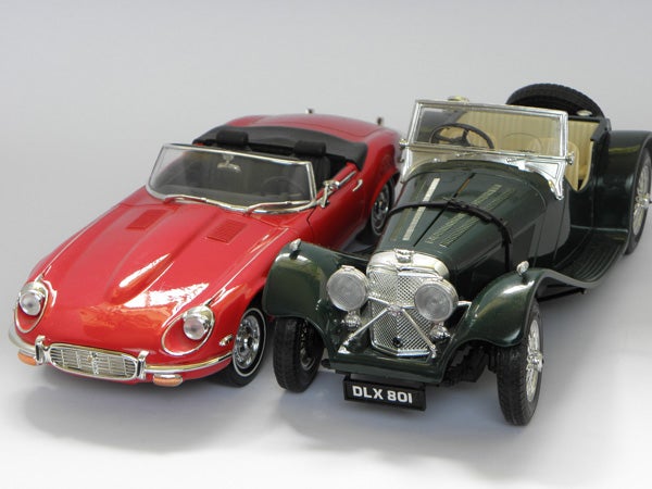 Photo of two model cars, a red sports car and a green classic car.