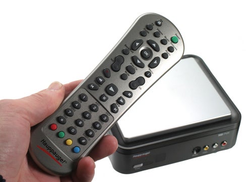 Hand holding Hauppauge HD PVR remote with device in background.