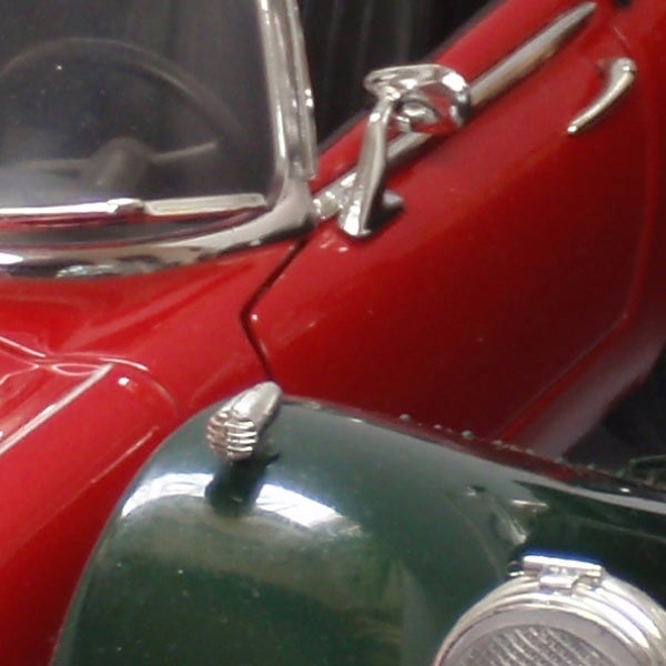 Close-up of vintage red and green cars with chrome details.