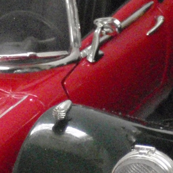 Close-up of vintage red car captured with Olympus mju 9000 camera.