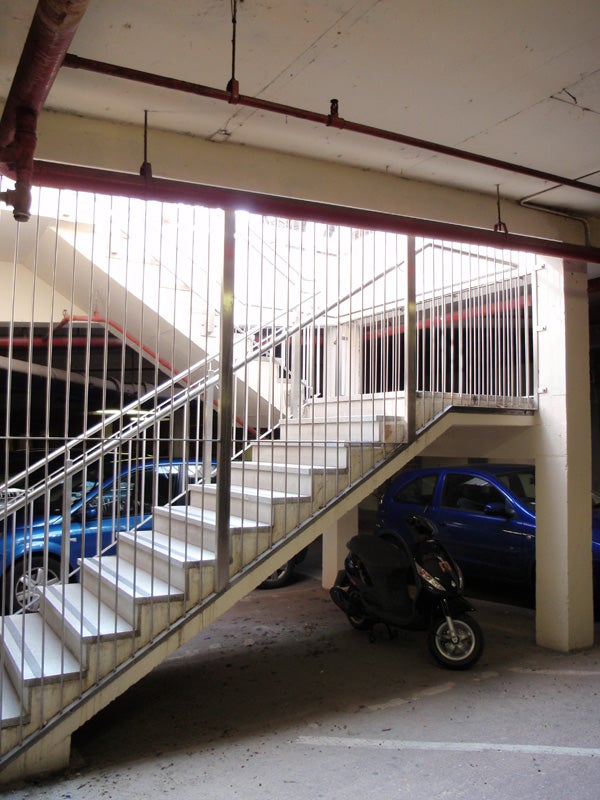 Parking garage interior with stairwell, cars, and scooter.
