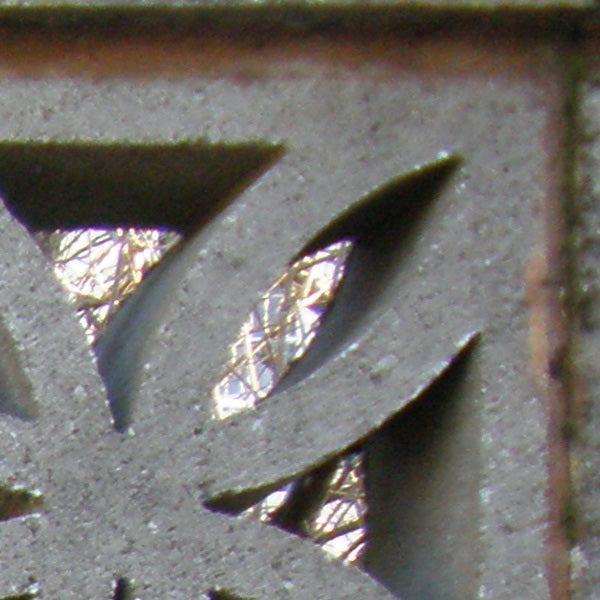 Close-up of metallic object with triangular cutouts showing background.