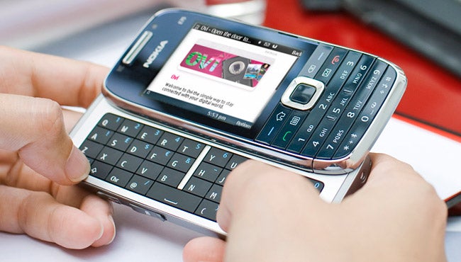 Person using a Nokia E75 smartphone with slide-out keyboard.