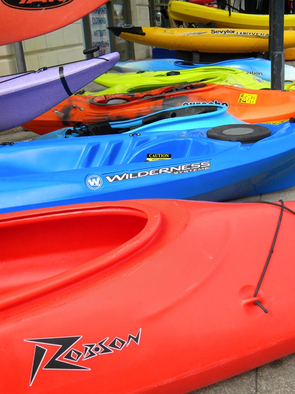 Colorful kayaks stacked on display outdoors.
