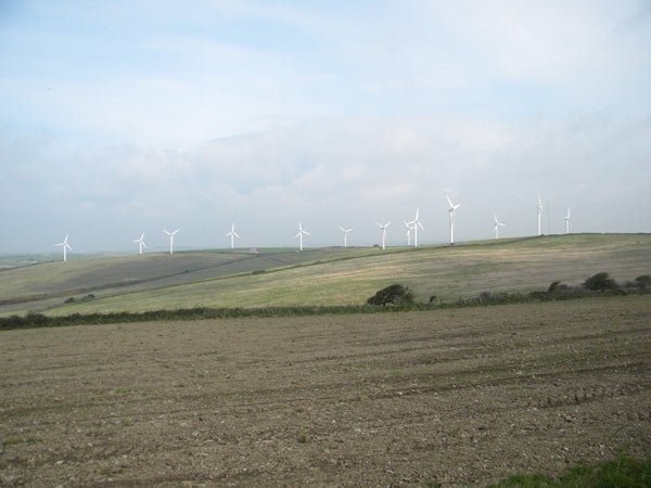 Landscape photo with wind turbines under overcast sky.