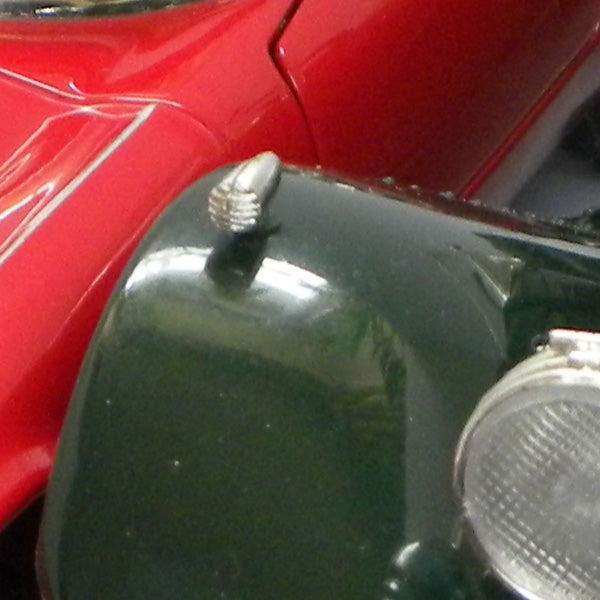 Close-up of a vintage car hood ornament and headlight.