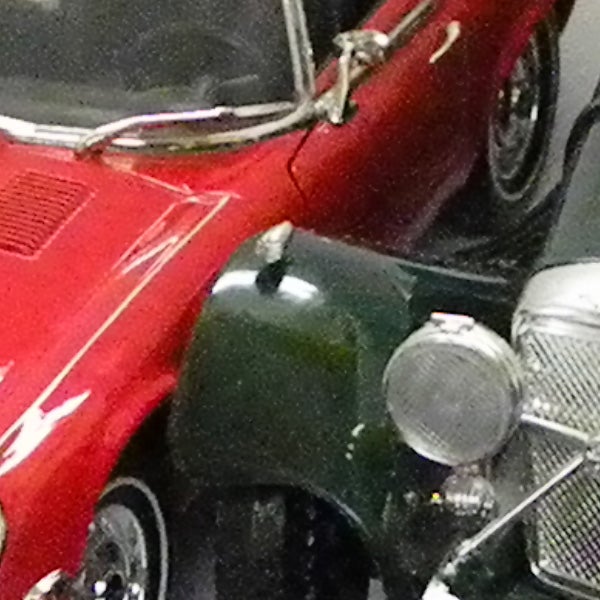 Close-up of a red vintage car's front section with chrome details.