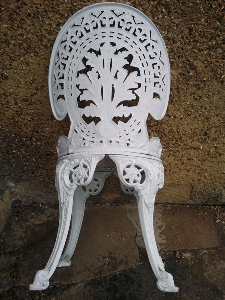 White intricately designed metal chair on a pavement.
