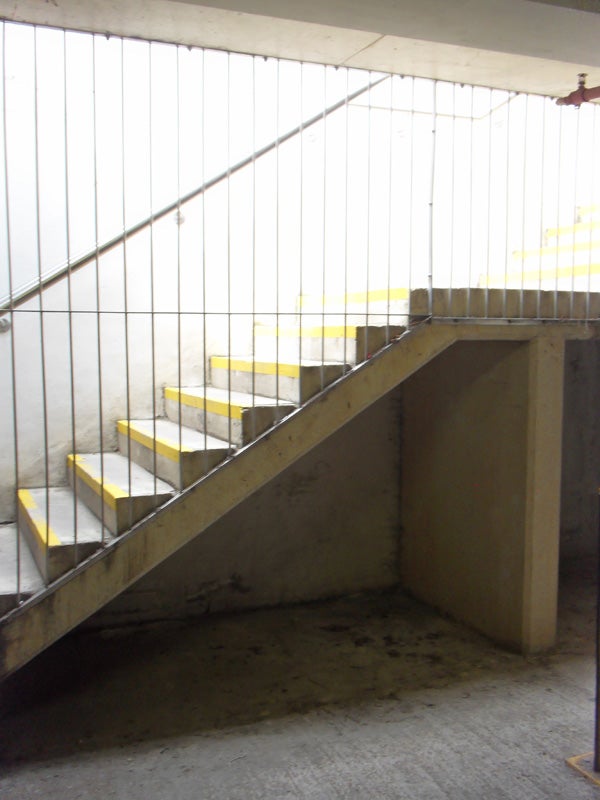 Concrete stairwell with metal railing and yellow edge markings.