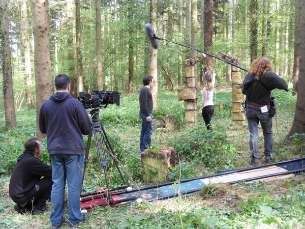Film crew recording in a forest setting.