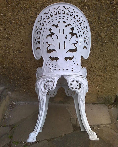 White ornate cast iron chair on a paved surface