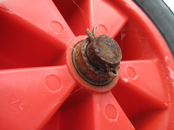 Close-up of rusty bolt on red plastic surface.