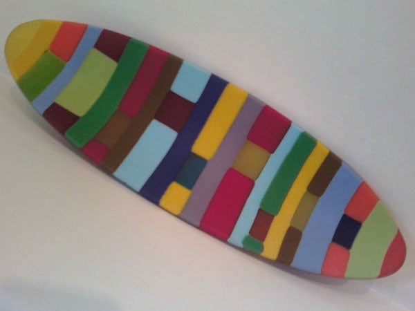 Colorful patterned surfboard on a white background.