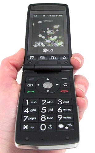 Hand holding an open LG KF300 mobile phone.