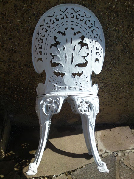 White ornate metal chair against concrete background.