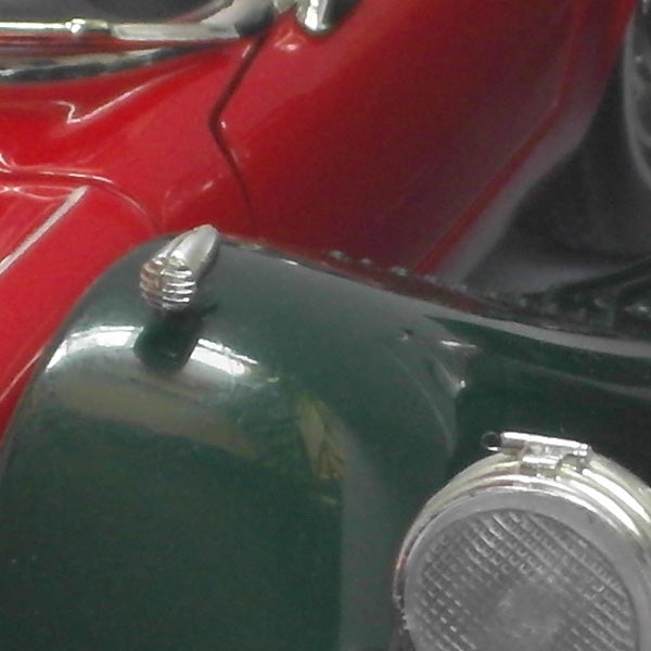 Close-up of a vintage red and green car hood and headlights.