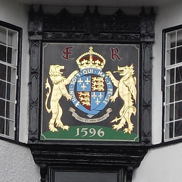 Ornate crest with lions and a crown on a building facade, dated 1596.