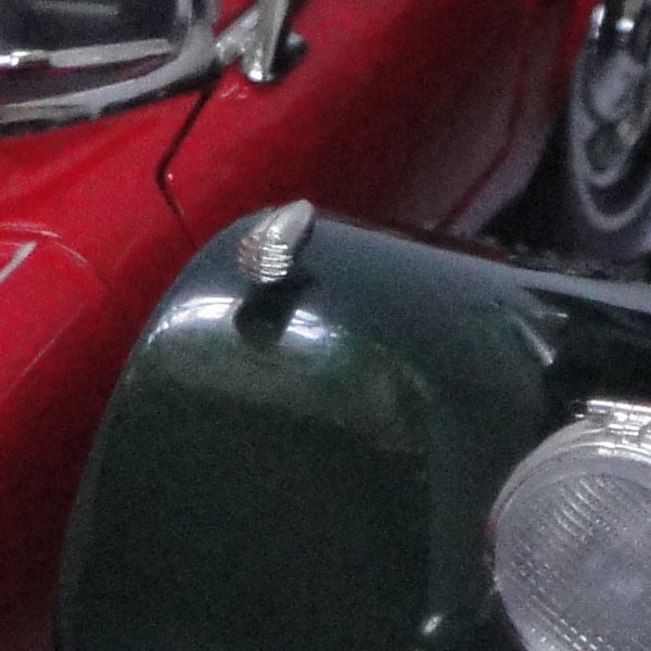 Close-up of a vintage car headlight and grille.