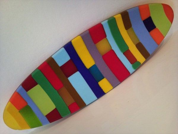 Multicolored abstract patterned surfboard on white background