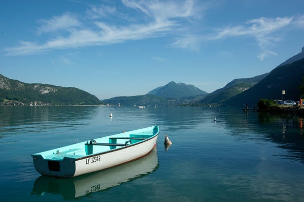 Boat on calm lake with mountains in the background.
