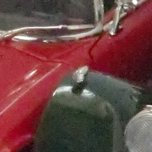 Close-up of a shiny metallic object with red background.