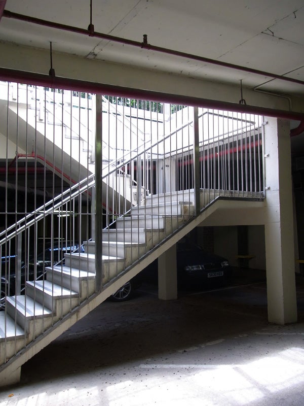 Concrete parking garage with staircase and parked cars.