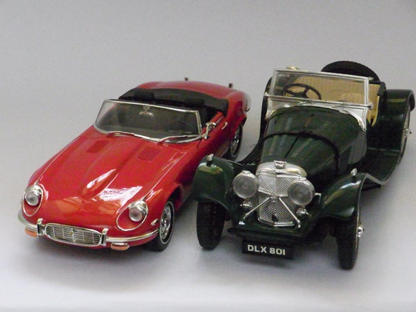 Two vintage toy car models, red and green, displayed side by side.